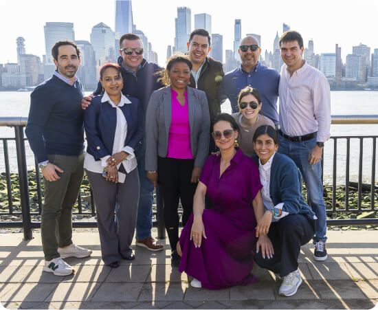 Un grupo de empleados de Colgate-Palmolive sonríe frente a un pintoresco paisaje urbano, lo que refleja la arraigada cultura de la empresa.